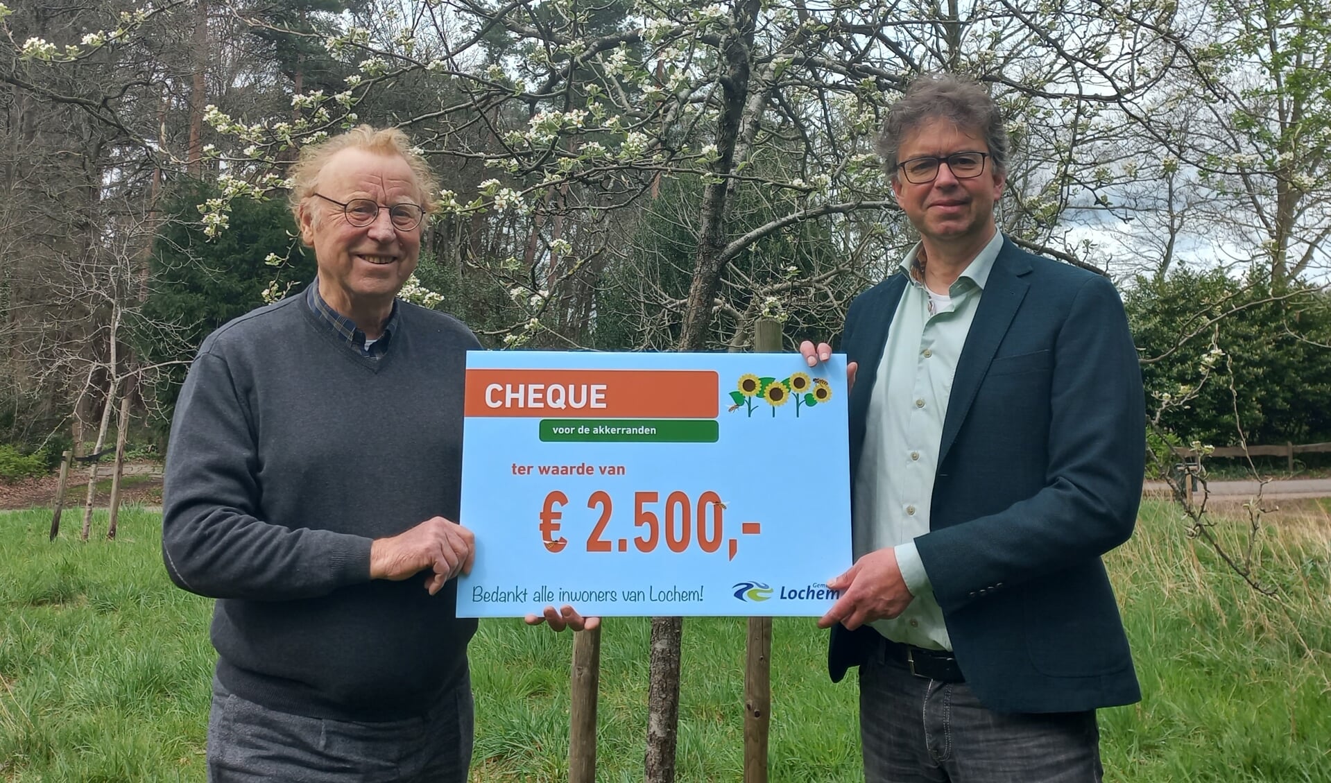 Wethouder van Zeijts (r) overhandigt namens de gemeente Lochem een cheque van 2.500 euro aan Machuut Eversteijn, vrijwilliger en promotor van het Zonnebloemlint. Foto: PR