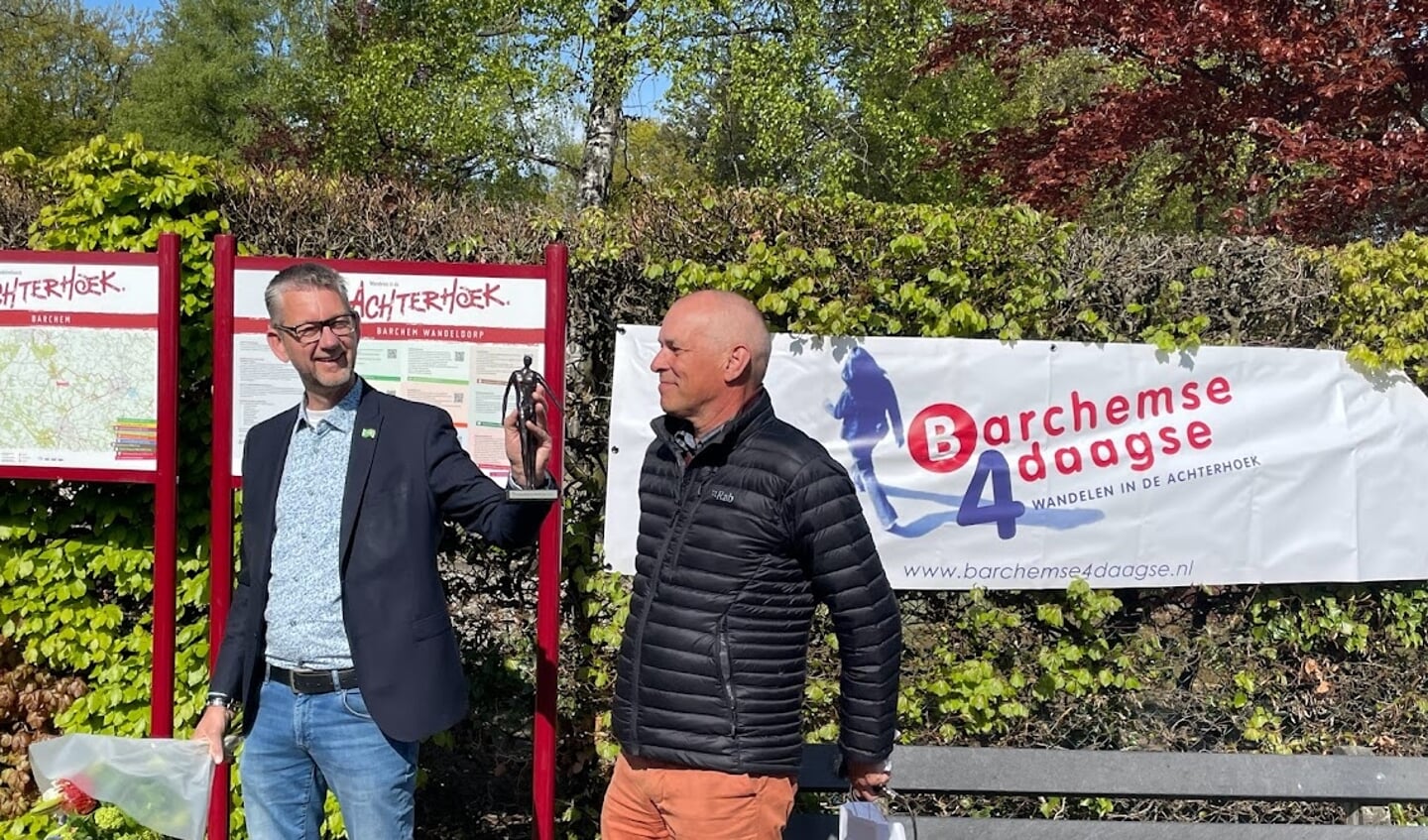 Wethouder Eric-Jan de Haan toont de trofee die hoort bij de titel Wandelgemeente van het Jaar. Rechts staat uitgever Eef van den Brink van wandelkrant Te Voet, dat de titelstrijd jaarlijks organiseert. Foto: Henri Bruntink