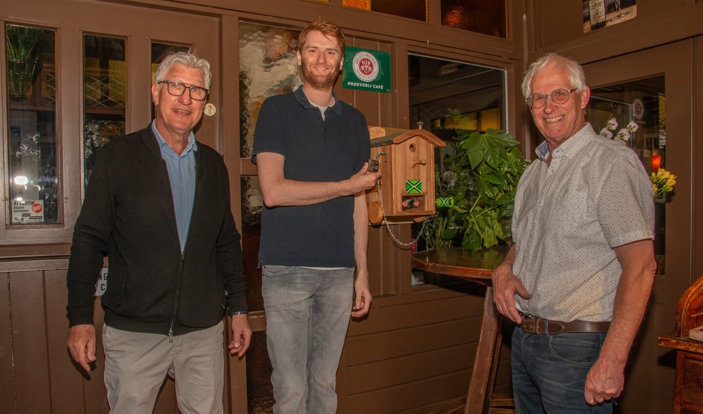 Paul Winterink, Bob Winterink en Wim Rutten hangen het ‘Kraak de code’ kastje in de hal van De Tol. Foto: Liesbeth Spaansen