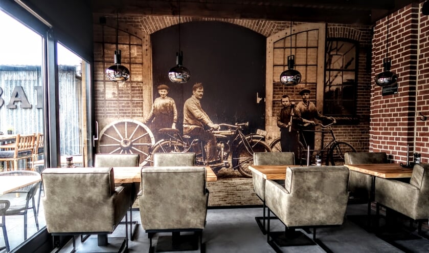Eén van de wanden in de bistro is aangekleed met een foto uit 1922, waarop ook de vroegere smid Bernard Jansen (op de motor) te zien is. Foto: Luuk Stam