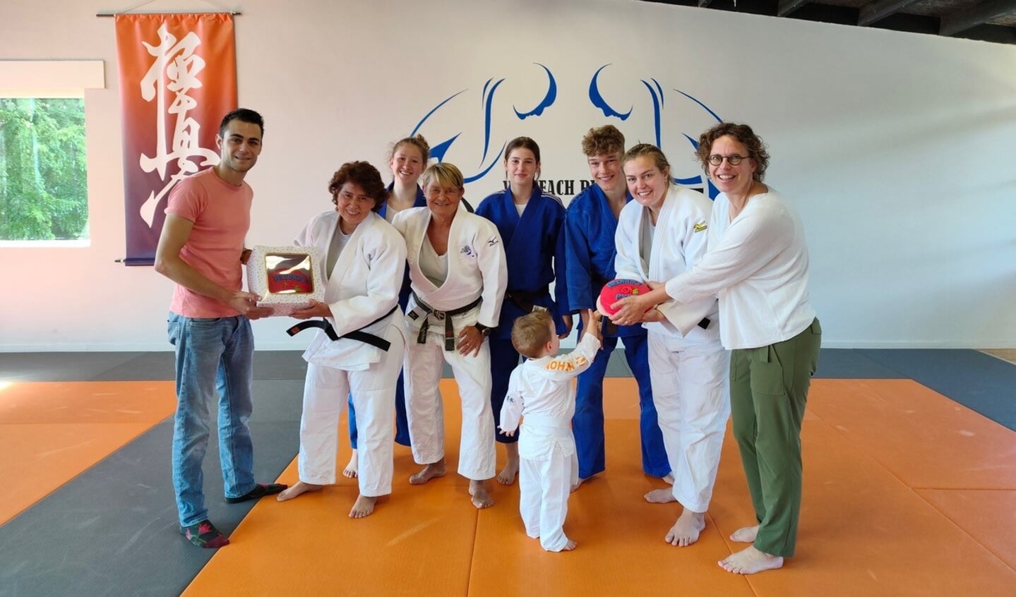 Tamim Mehdi, raadslid PvdA, overhandigt de rode taart aan het trainersteam van Judo Zutphen. Foto: PR