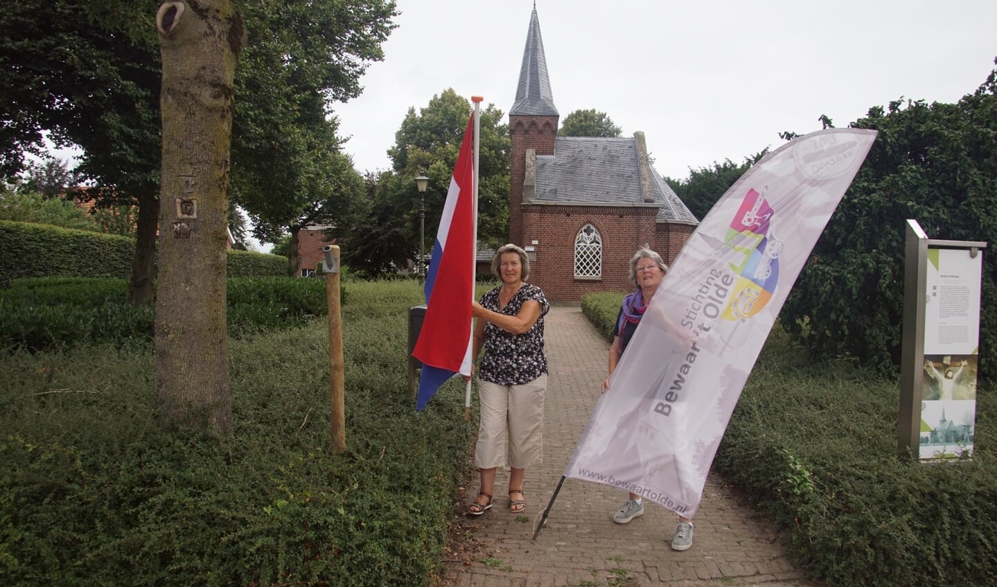 Thea Veerbeek (links) met Johanna Hesselink met vlag en banier voor kerkje De Rietstap. Foto: Frank Vinkenvleugel