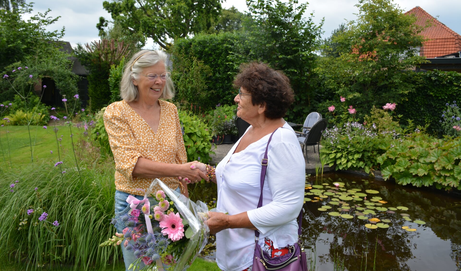 Joke Meulenveld ontvangt een attentie en een bos bloemen uit handen van voorzitter van Vrouwen van Nu Wilma Aalderink. Foto: Diny Oosterlaken