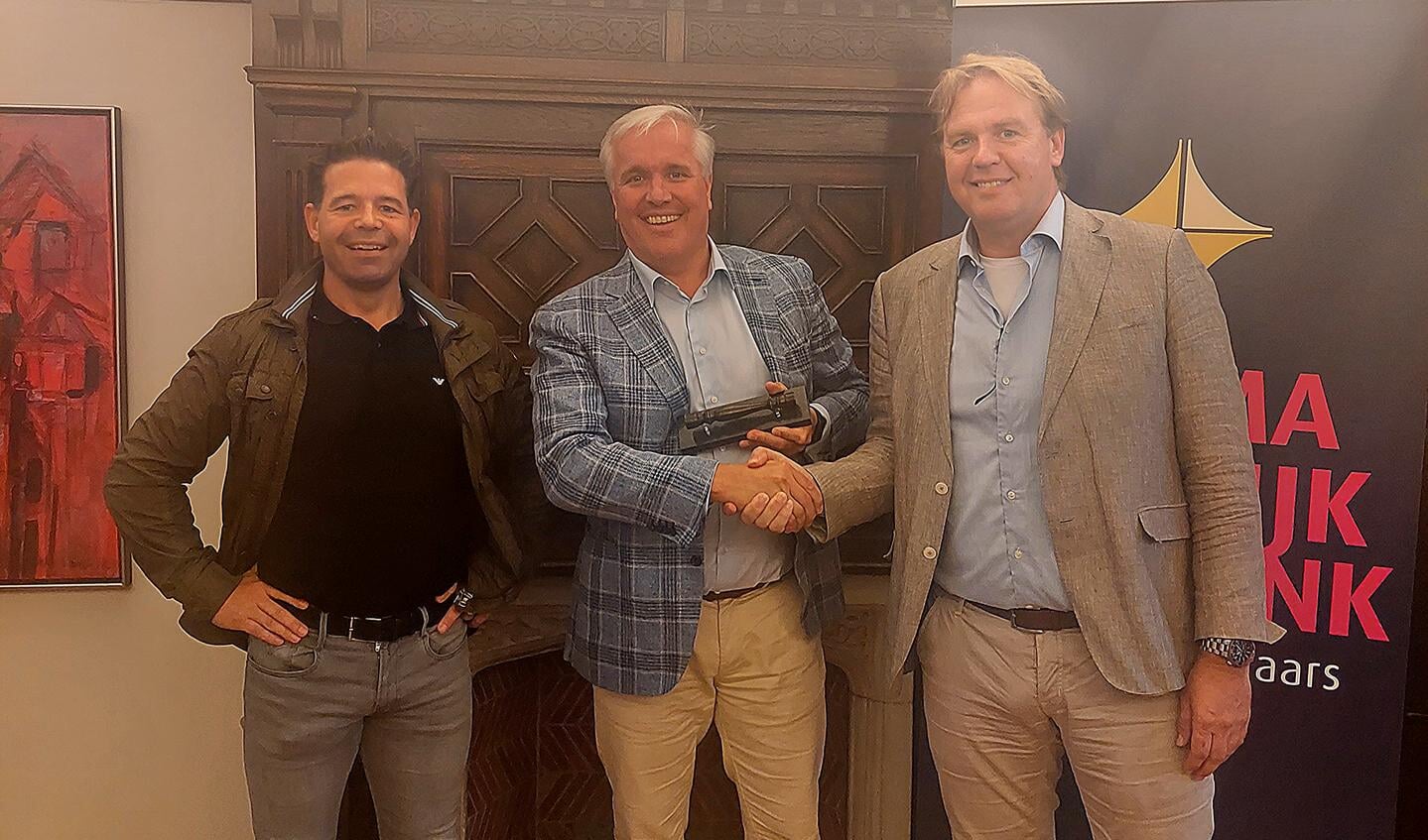 Mr. Rob Kranen (rechts) en Dylan Mulders (links ) overhandigen John van Dijk zijn makelaarsstafje.