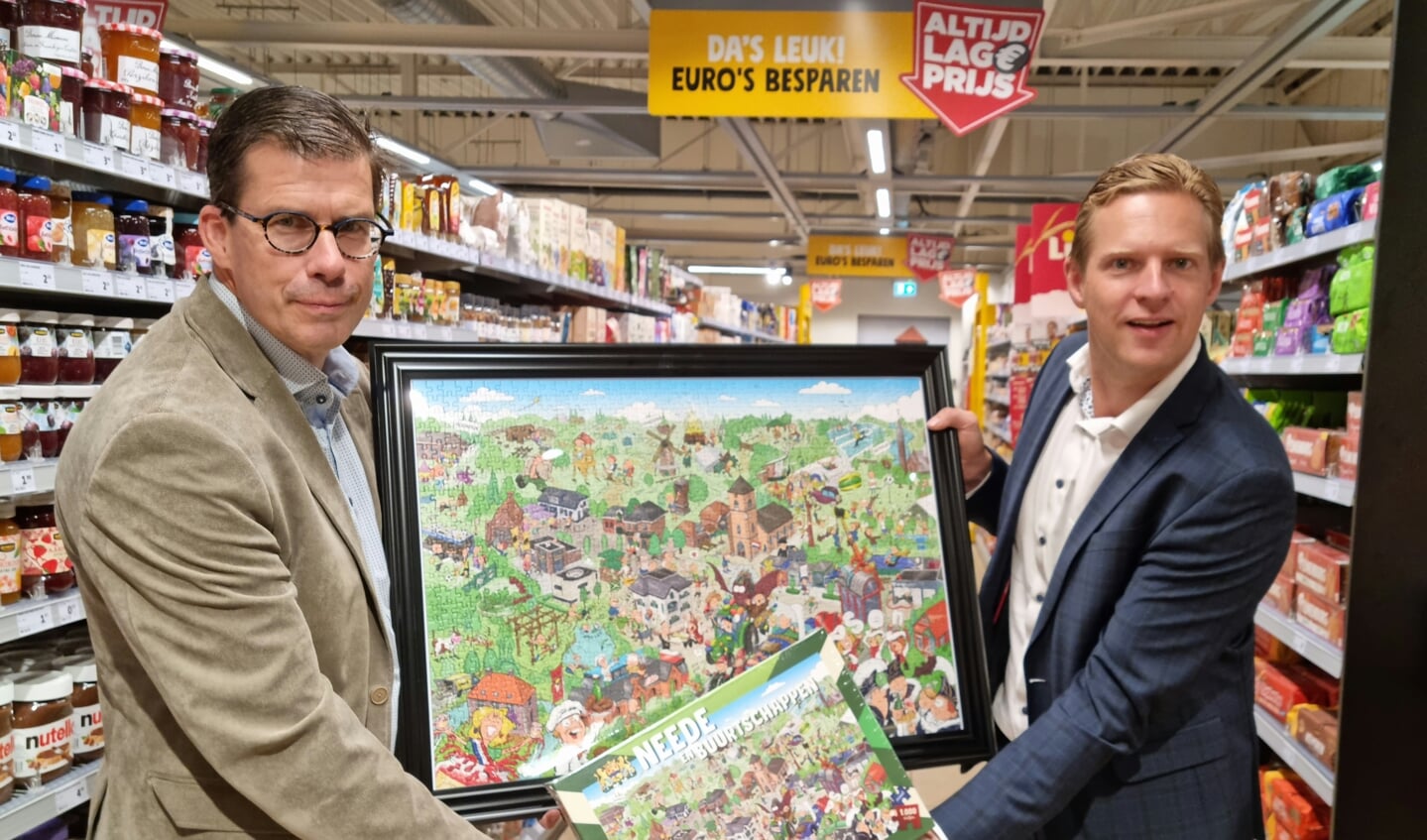Burgemeester Joost van Oostrum en Jumbo-eigenaar Tijn Leussink tonen de nieuwe Neede-puzzel. Foto: Rob Weeber