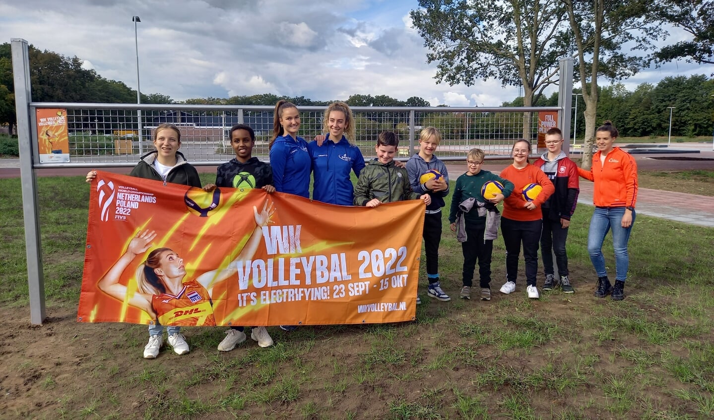 De jongeren van Jimmy’s en de trainsters van volleybalvereniging Gemini met de banner van het WK Volleybal bij het buitensportnet op sportpark De Wildbaan. Foto: PR