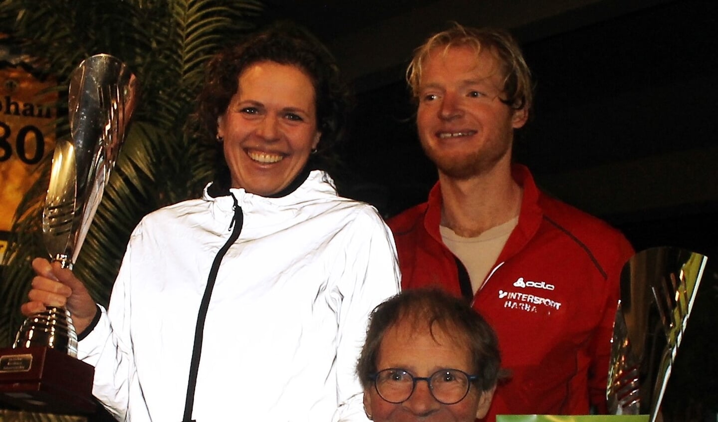 Ton ten Have (m) reikt de wisselbeker uit aan Steven den Besten (r) en Ilse Winkel als snelste deelnemer uit Vorden op de 15 km. Foto: Leon Rinders