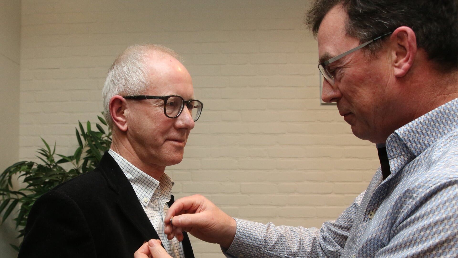 Vicevoorzitter Daniël Hakvoort speldt Gerrit Burkink de versierselen op die behoren bij het 40-jarig lidmaatschap. Foto: Theo Frencken