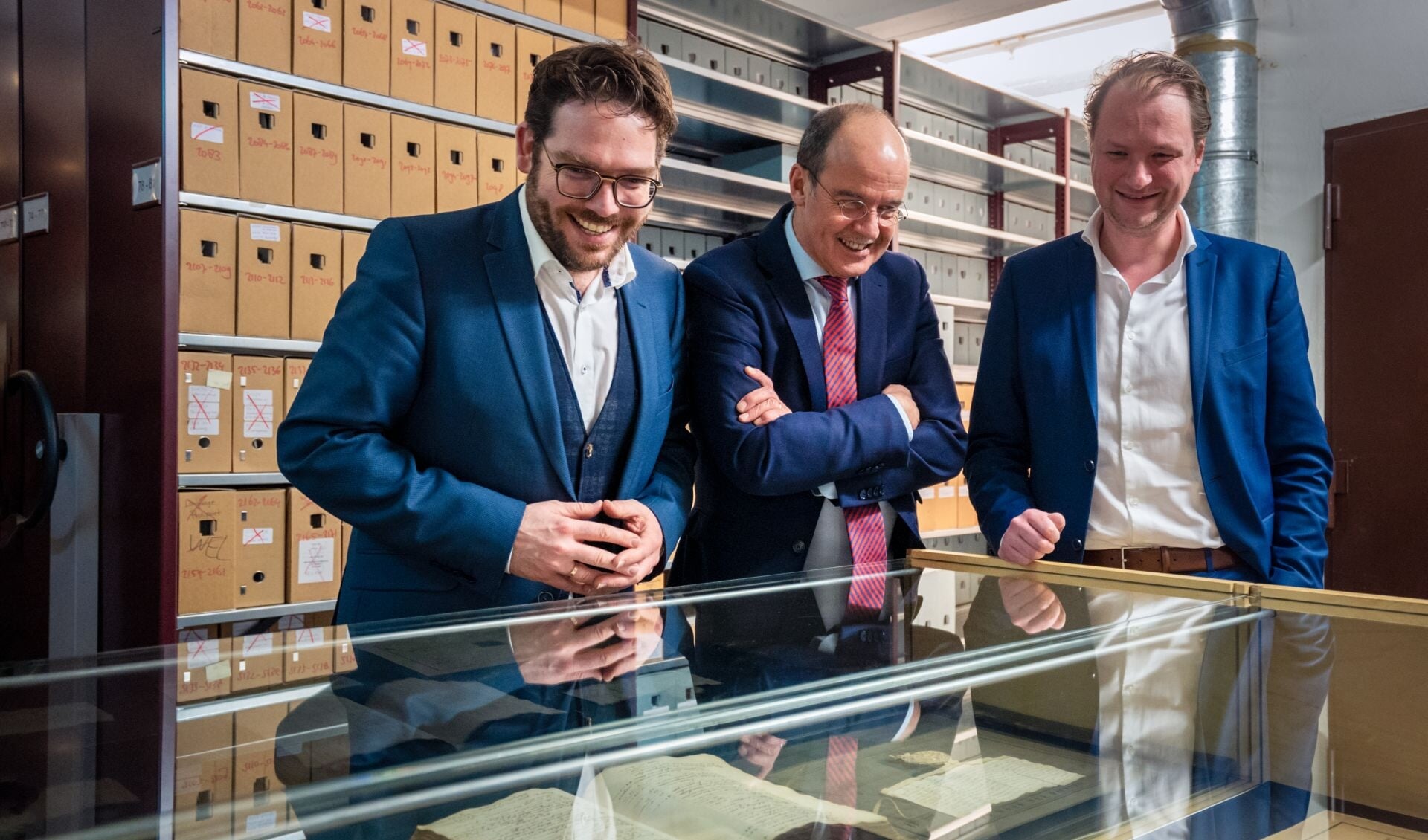 Burgemeester Sebastiaan van ’t Erve (Lochem), burgemeester Alex van Hedel (Brummen) en locoburgemeester Sjoerd Wannet (Zutphen) krijgen een rondleiding door het depot van het Regionaal Archief Zutphen, nadat ze de samenwerking voor drie jaar hebben verlengd. Foto: Jolanda van Velzen