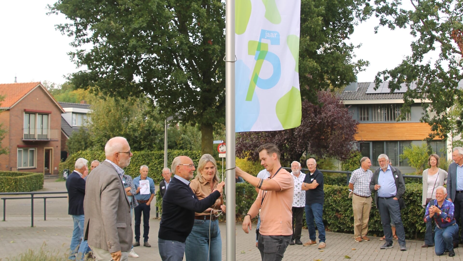 Leerling van het eerste uur, Joop Kothuis en rector Gittie Burema hijsen de jubileum-vlag. Foto: Annekée Cuppers