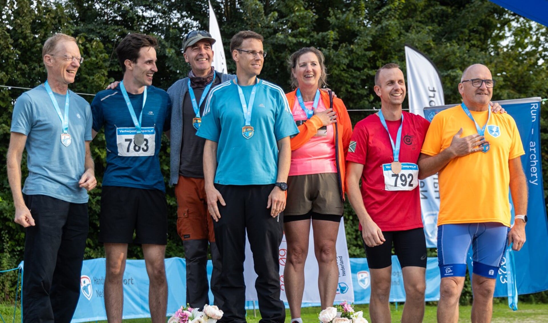 Henri Polman (masters) en Jorik Klein Nijenhuis (Heren), op plek 3, genietend van de tonen van het Wilhelmus door een delegatie van de Swingende Infuustoeters voor de Nederlands Kampioenen Run-Archery 2023. Foto: Tim Bruijninckx