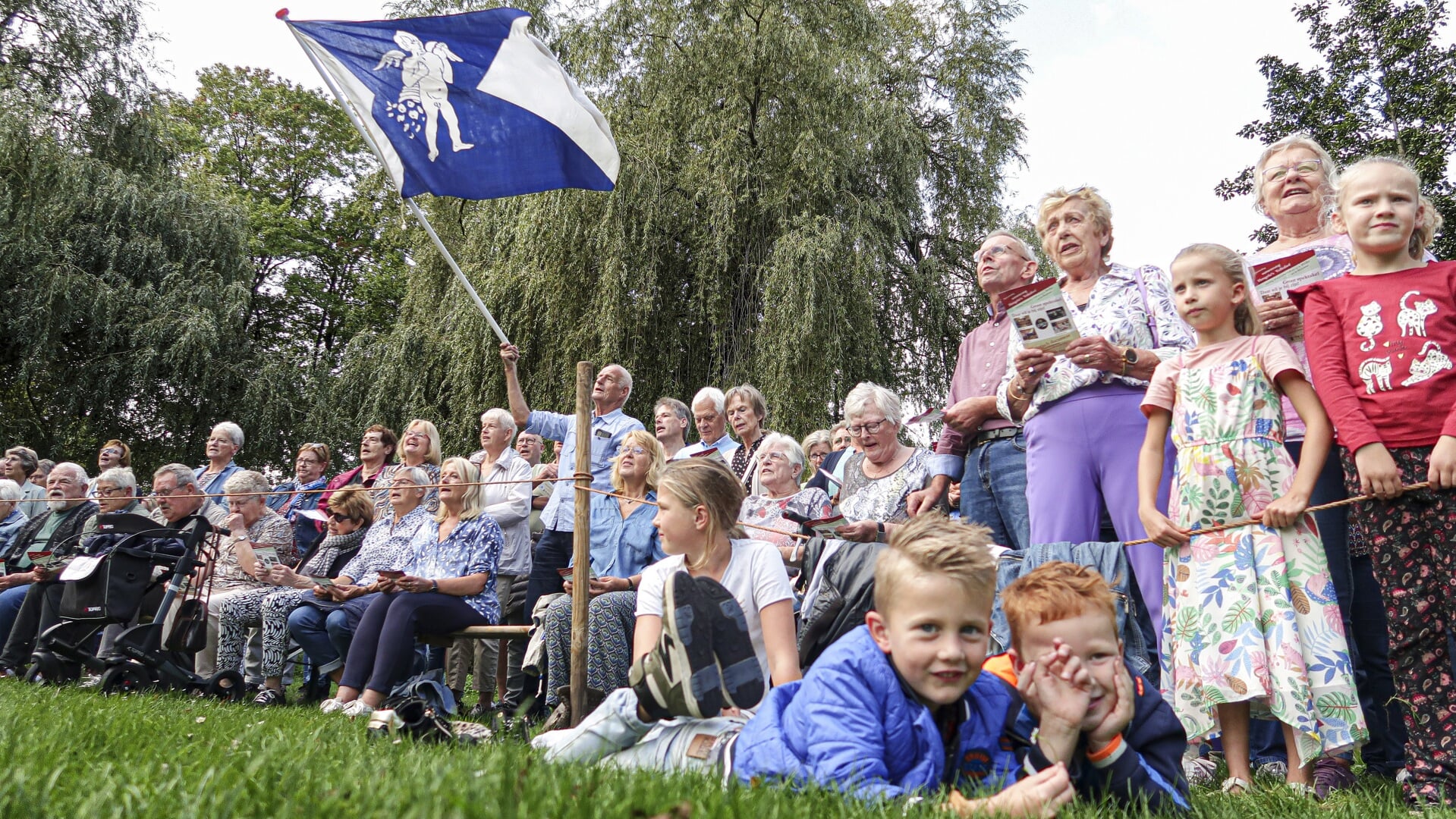 De vlag met daarop het wapen van de voormalige gemeente Hengelo zwaait door de lucht tijdens het zingen van het volkslied op de Bleek. Foto: Luuk Stam
