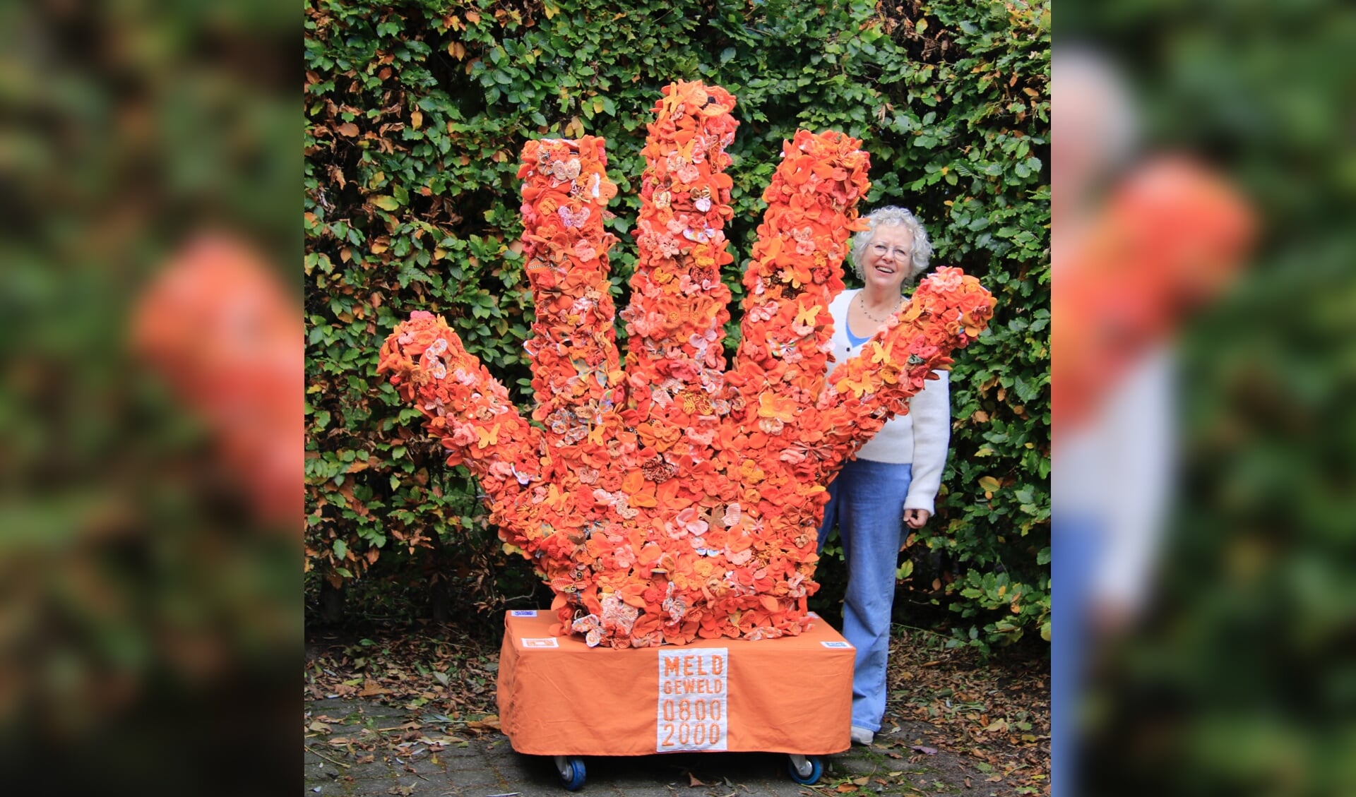 Hanneke van der Werf bij de driedimensionale hand met 1500 oranje vlinders. Foto: Annemarie Paalvast