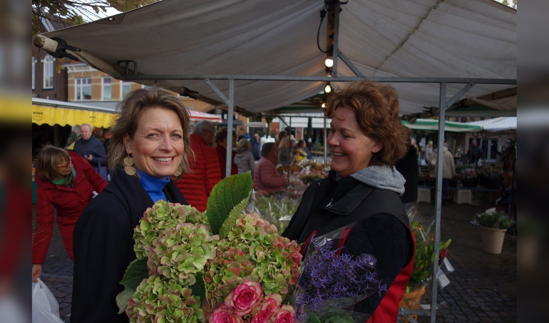 Links Ilse en rechts Carina Jansen , die op de markt een mooi bosje bloemen voor haar heeft. Foto: Clemens Bielen