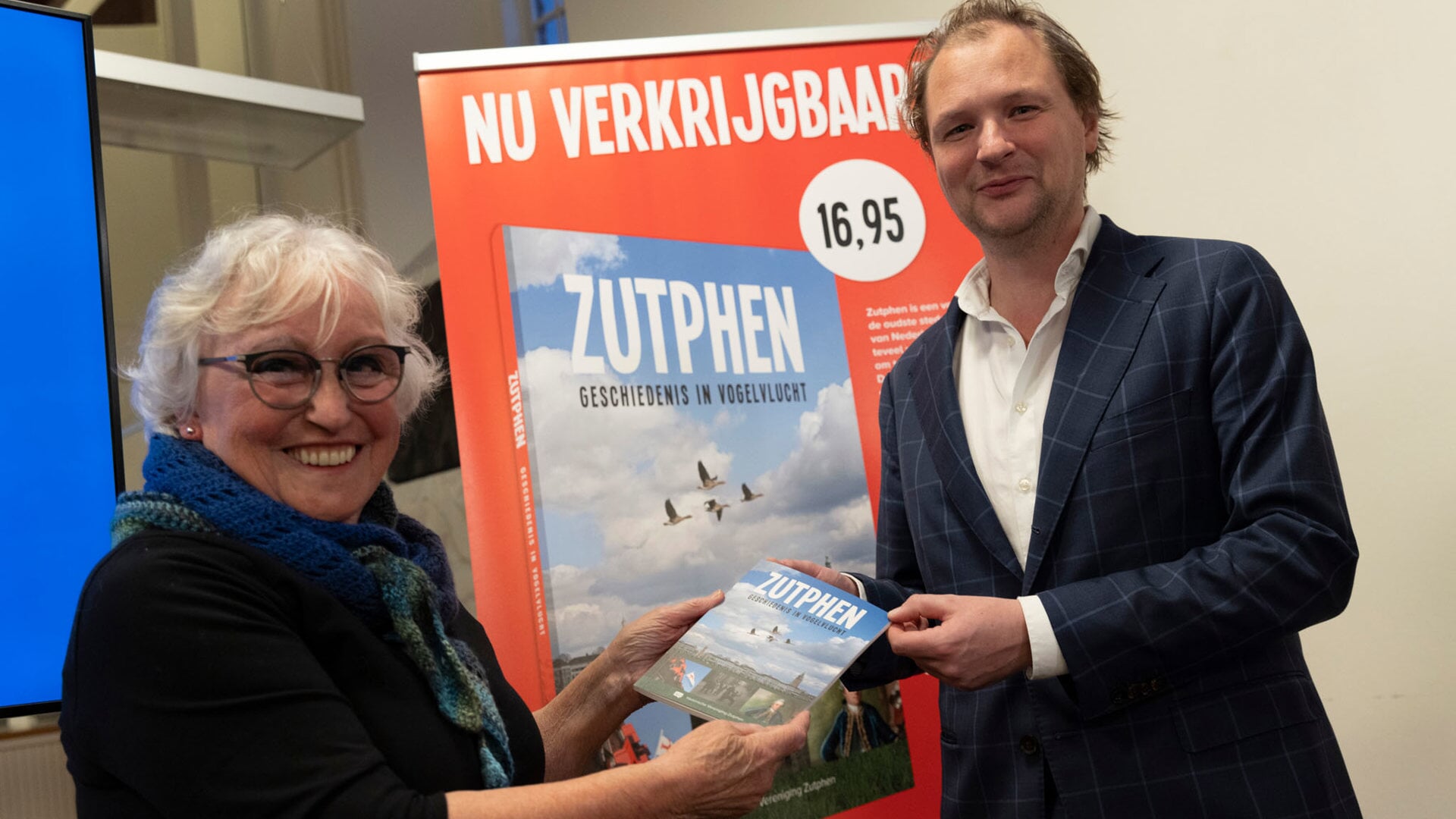 Bini Jansen, bestuurslid van de Historische Vereniging Zutphen, overhandigt het eerste exemplaar aan wethouder Sjoerd Wannet. Foto: Patrick van Gemert/Zutphens Persbureau