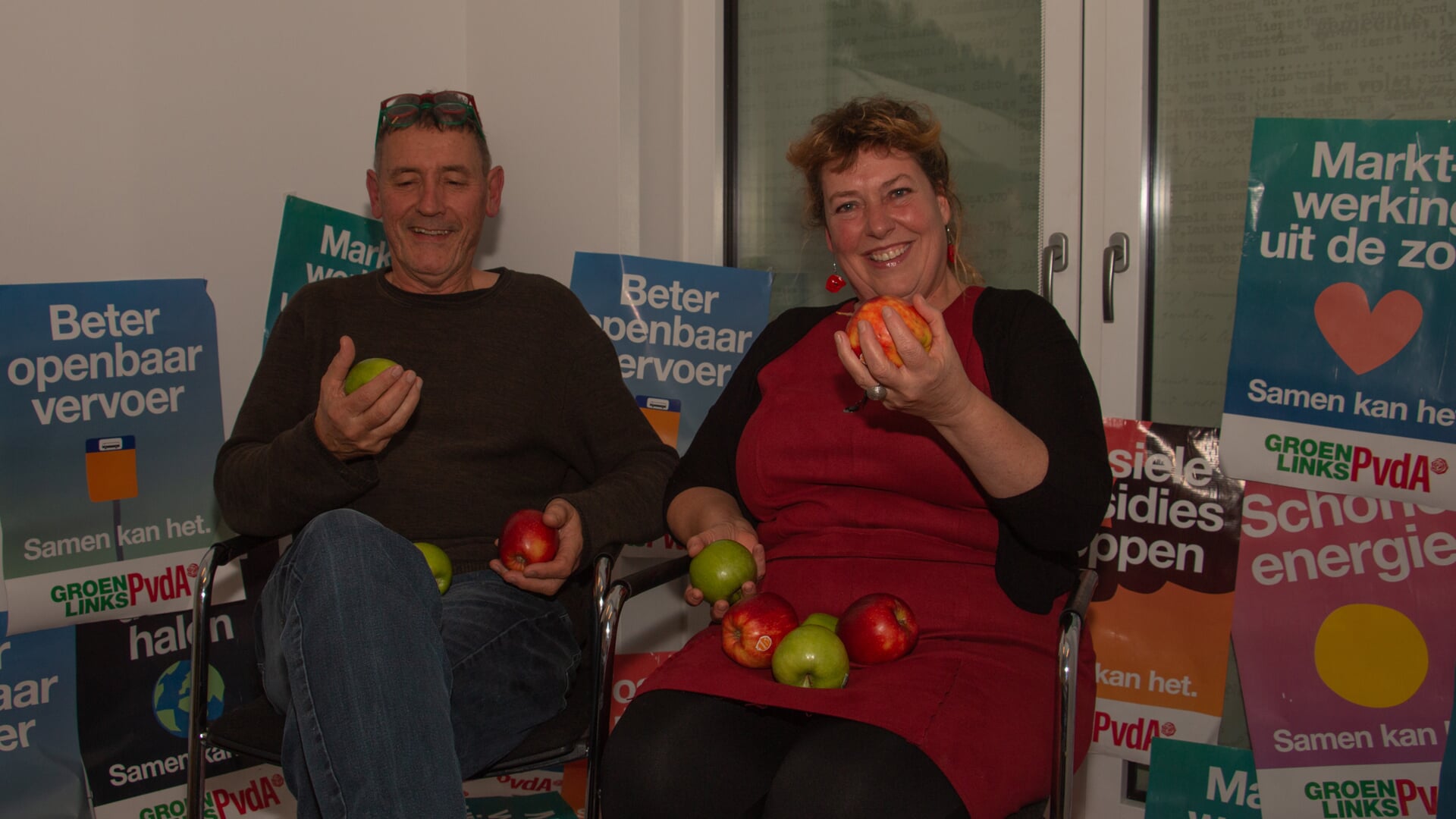 Fractievoorzitters Ulrike ter Braak van GL en Luuk Preijde van PvdA gebruiken posters om te laten weten waar ze samen voor staan, en delen geen rozen uit maar rode en groene appels. Foto: Liesbeth Spaansen