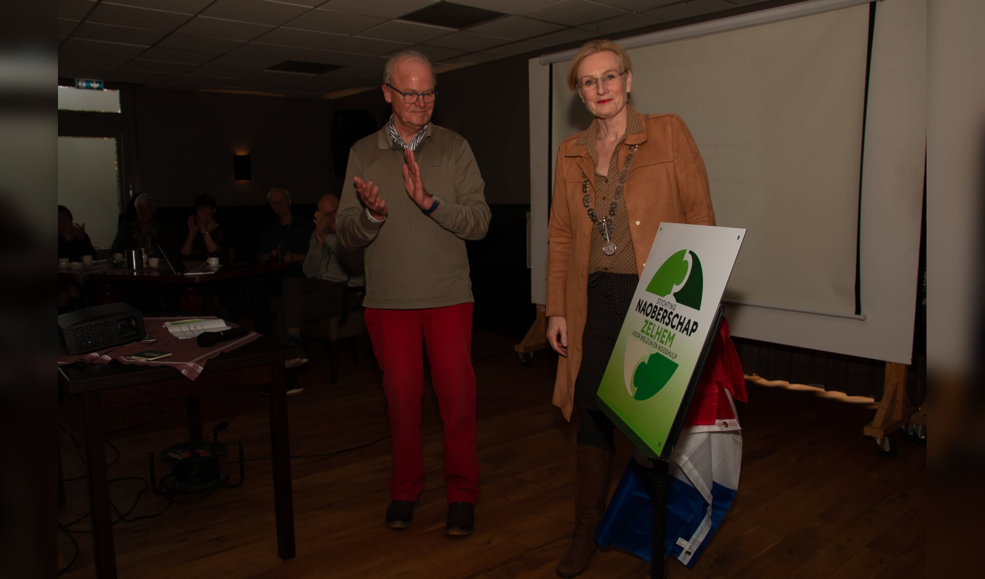 Het nieuwe logo van Stichting Naoberschap Zelhem is onthuld door burgemeester Besselink. Naast haar de voorzitter Niek Willemsen. Foto: Liesbeth Spaansen