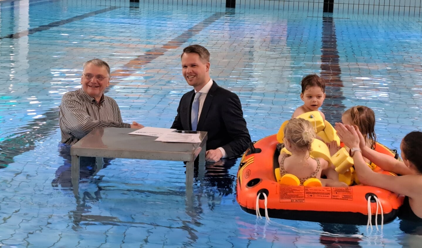 Voorzitter Frits van Lochem en wethouder Bart Porskamp ondertekenen, in het zwembad, het nieuwe contract. 