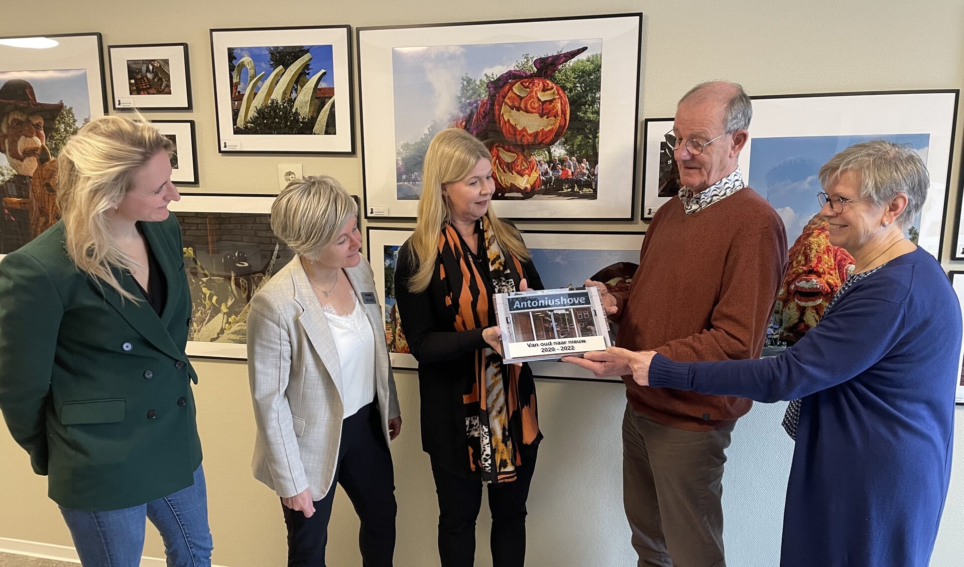 Aloys Berendsen overhandigt het fotoboek aan Anita Slutter. Op de achtergrond een aantal werken uit de huidige expositie van het Lichtenvoords Foto Collectief. Foto: Barbara Pavinati