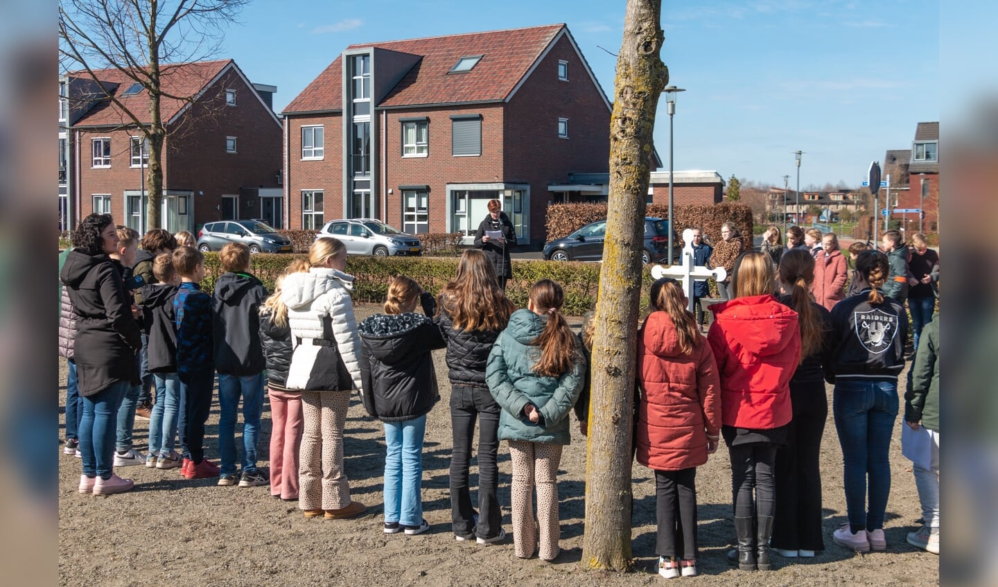 Leerlingen staat in een kring rond het Witte Kruisje en luisteren naar hun leerkracht. Foto: Henk Derksen
