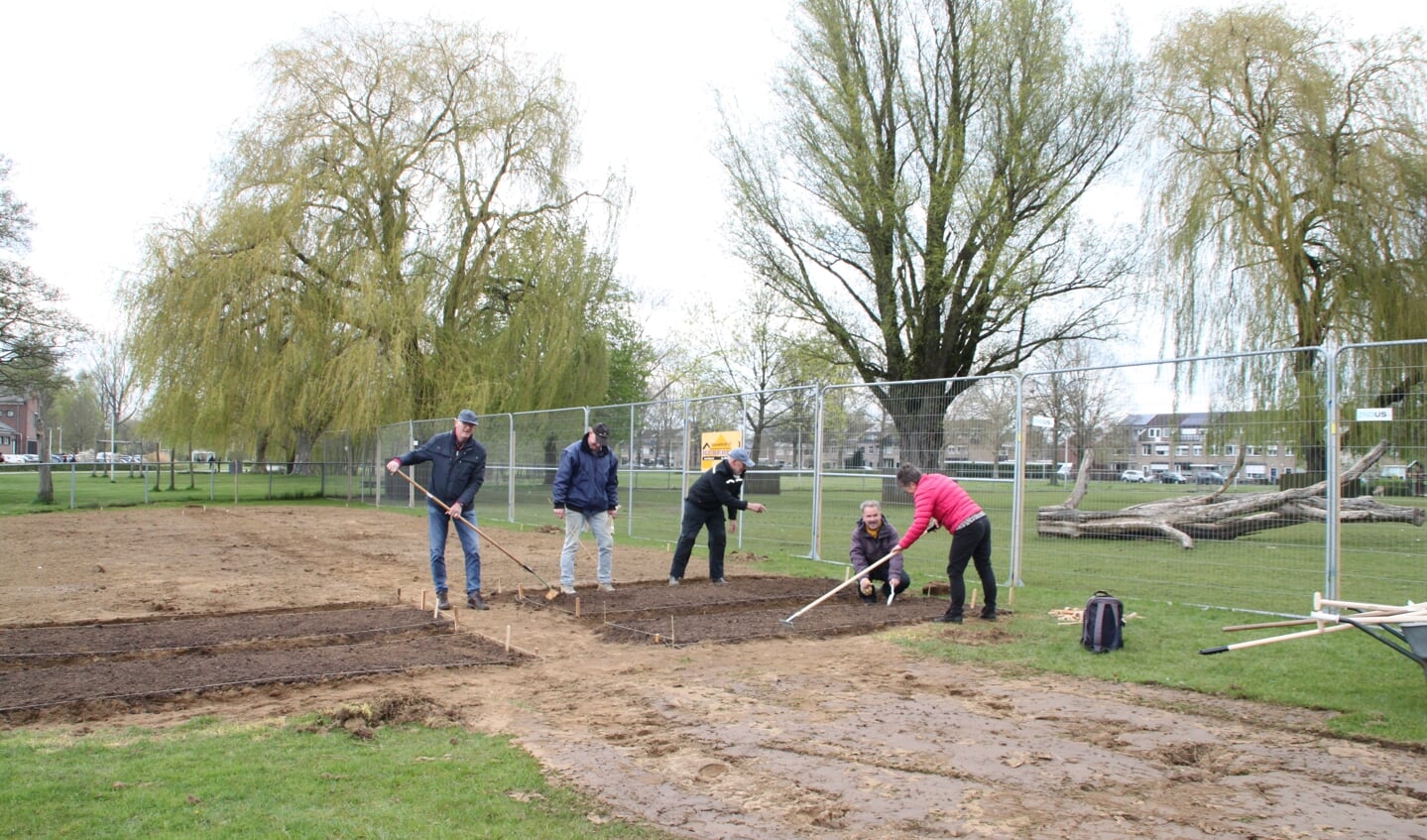 Vrijwilligers leggen de bio-moestuin aan in het Wentholtpark. Op de knieën Derk Huizinga.