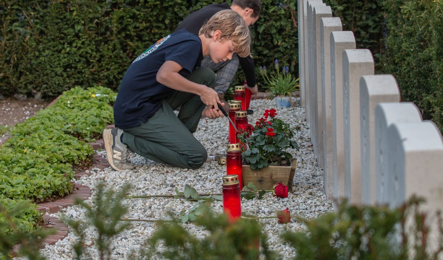 Miel en Torsten steken de kaarsen aan tijdens de  herdenking 4 mei op de begraafplaats in Steenderen. Foto: Liesbeth Spaansen