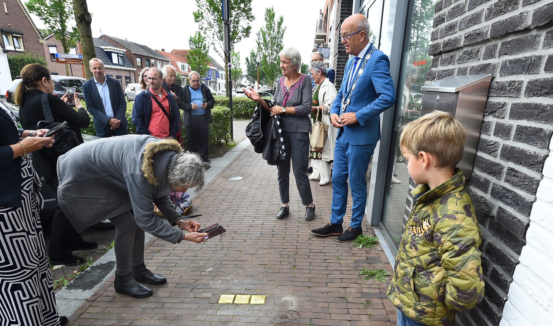 Rudy maakt een foto van de Stolpersteine terwijl haar kleinkind toekijkt. Foto: Roel Kleinpenning