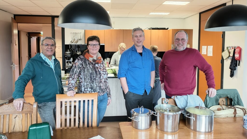 Theo Tetelepta, Esther Sonderen, Leander Grooten en Dick van Dijk in de keuken van Klimop. Op de achtergrond bereiden vrijwilligers de wekelijkse maaltijd. Foto: Sis Huiskamp