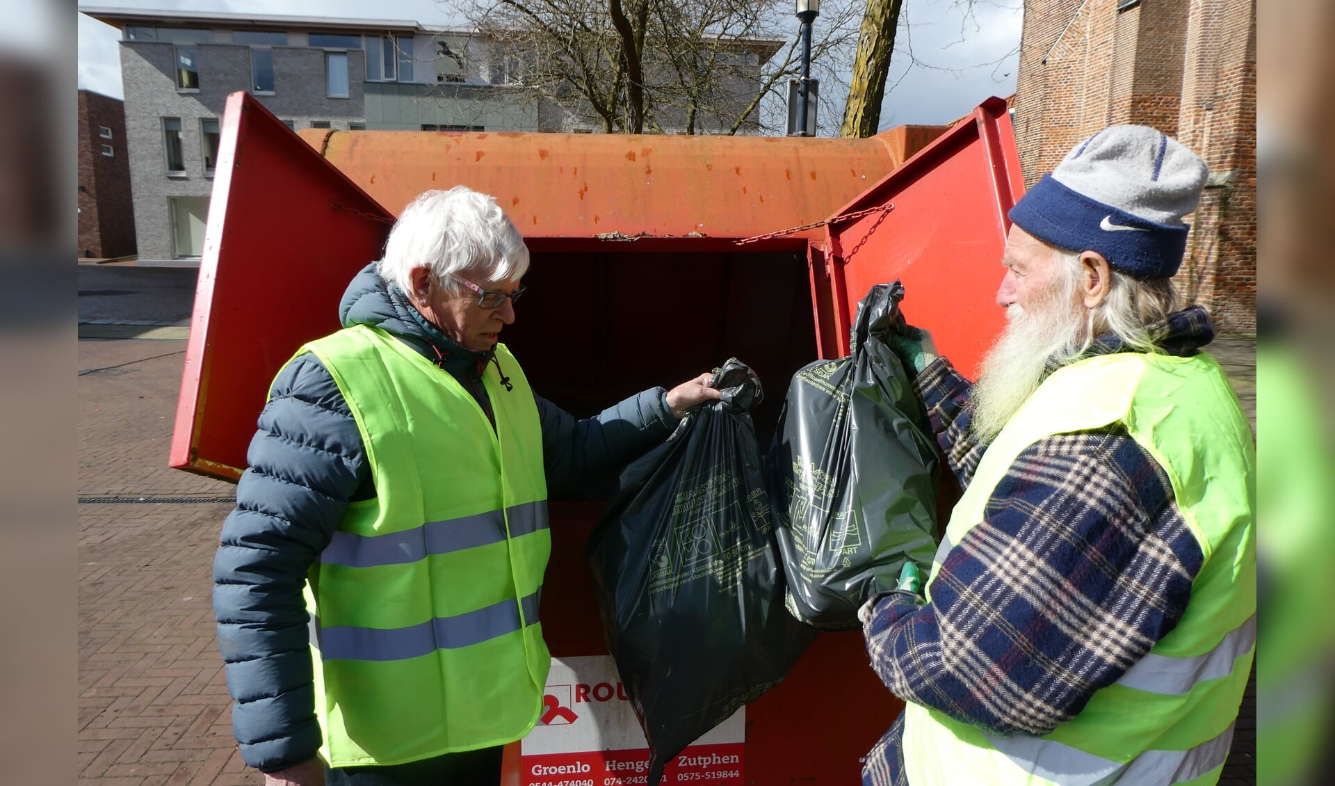 Harry Bosch en Stef Taken (r) gooiden zaterdag de laatste twee vuilniszakken met afval in de rode container. Foto: Jan Hendriksen