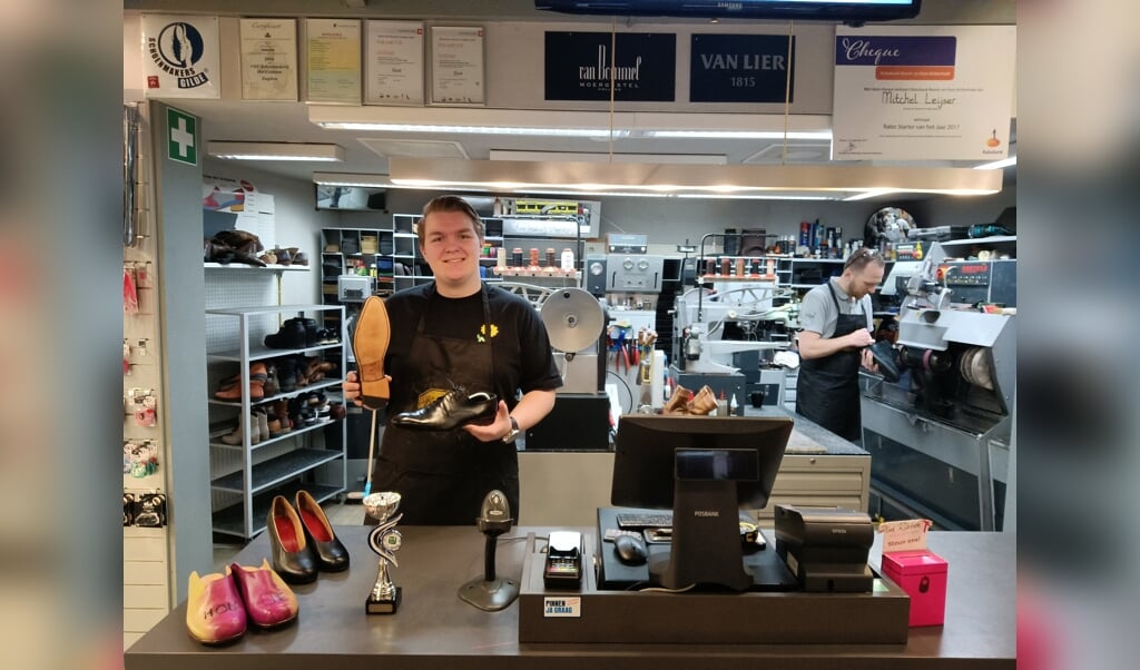 Axel Garritsen toont de door hem herstelde schoenen waarmee hij hoge ogen gooide tijdens de Europese Vakwedstrijd voor Schoenmakers 2024. Rechts zijn trotse werkgever, schoenmaker Mitchel Leijser van Schoenmakerij 't Centrum. Foto: Rudi Hofman