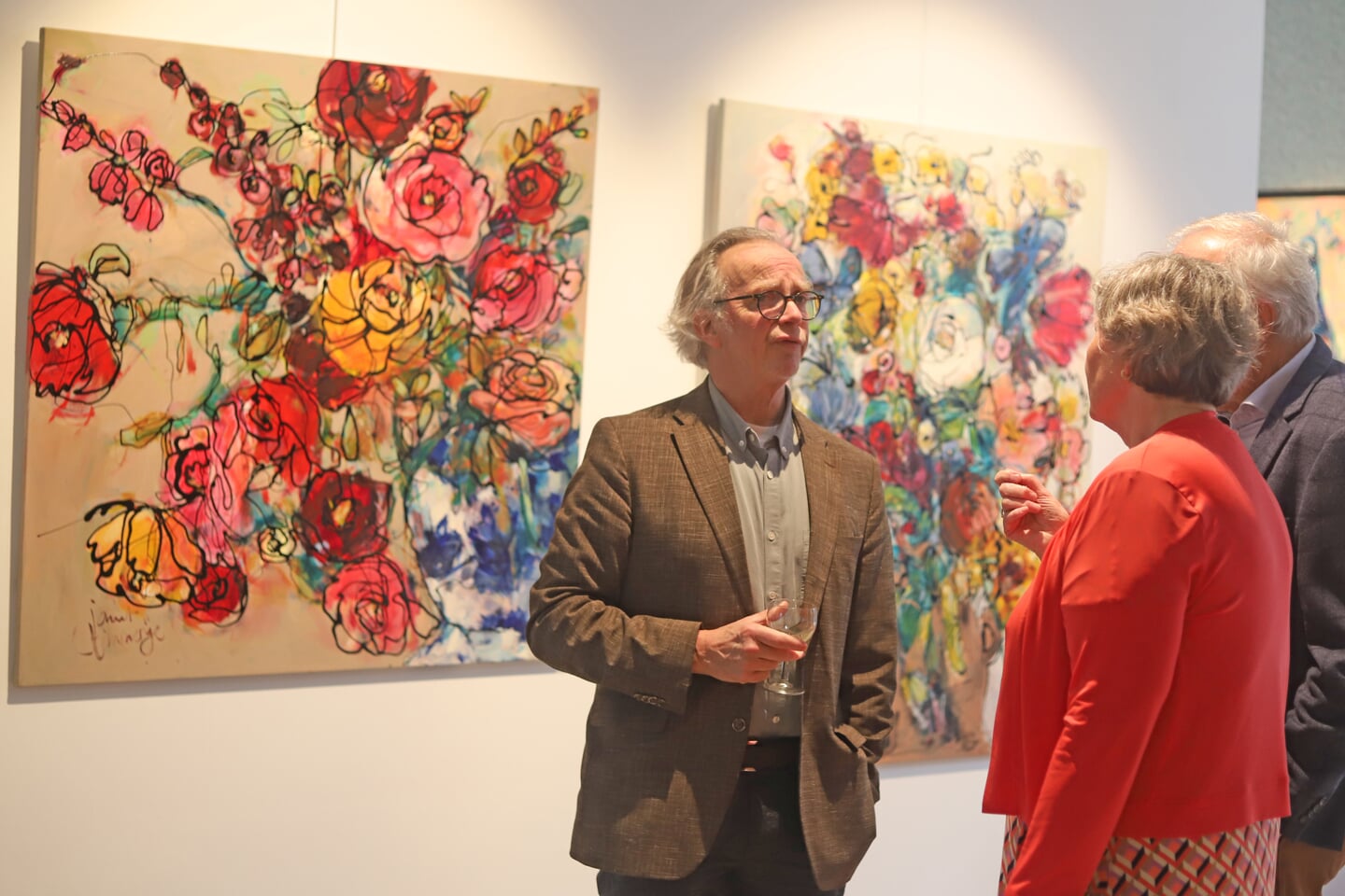 Kunsthistoricus Jaap Nijstad in gesprek met bezoekers. Twee schilderijen van Janet Timmerije vormen het decor. Foto: Sander Grootendorst