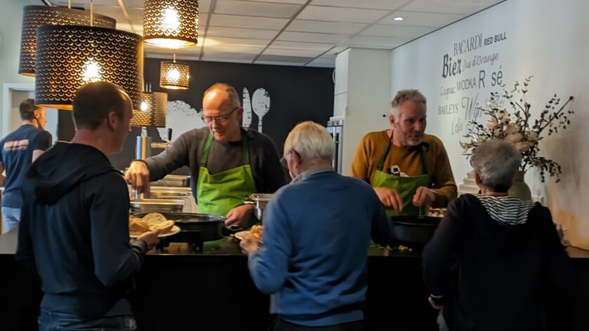 Vrijwilligers bakken eieren met spek tijdens het traditionele dorpsontbijt op Koningsdag 2023.
