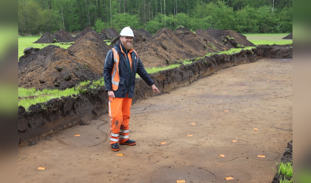 Archeoloog Folkert Westtra wijst de plekken aan waar de palen in de grond  stonden van een boerderij uit de ijzertijd. Foto: Arjen Dieperink