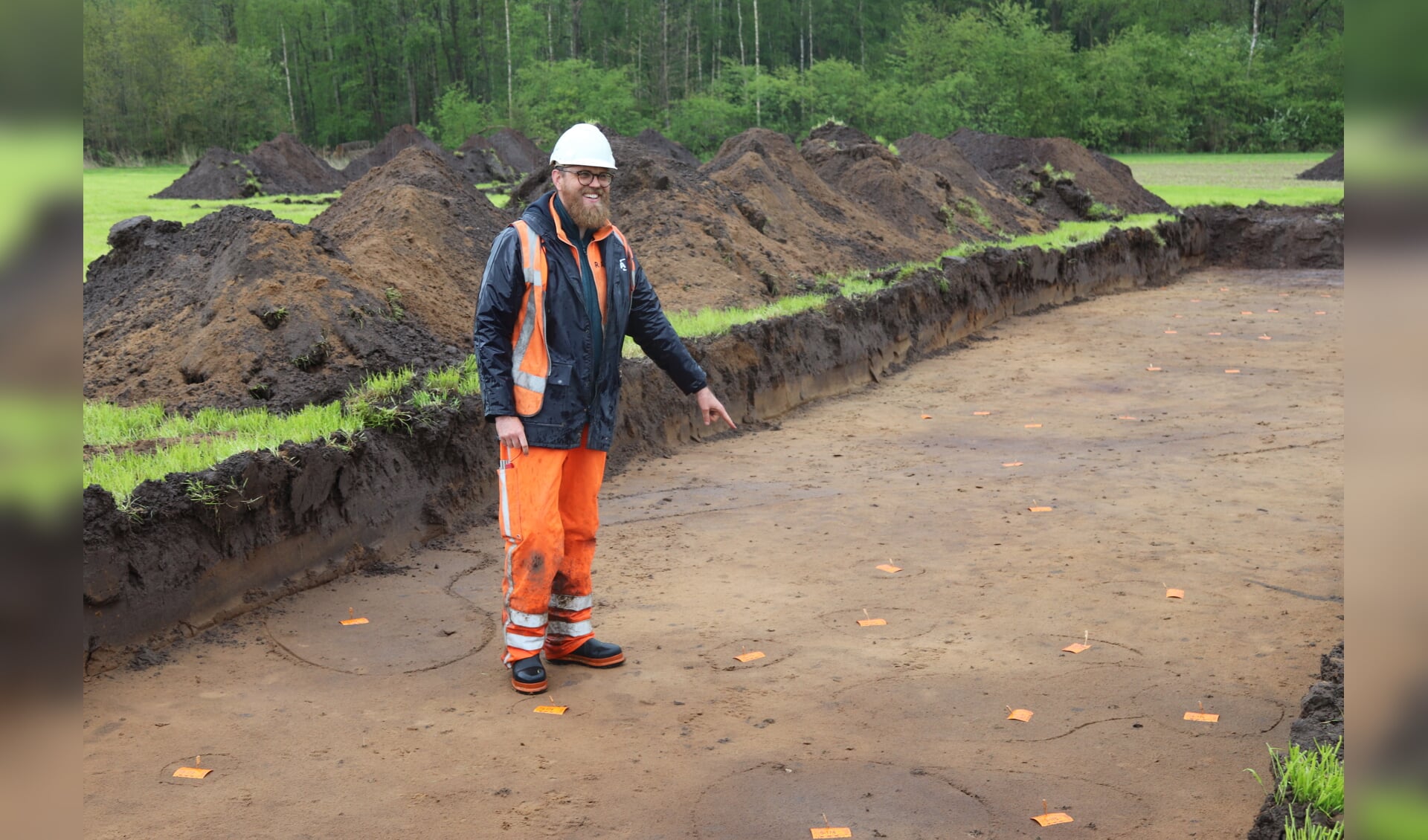 Archeoloog Folkert Westtra wijst de plekken aan waar de palen in de grond  stonden van een boerderij uit de ijzertijd. Foto: Arjen Dieperink