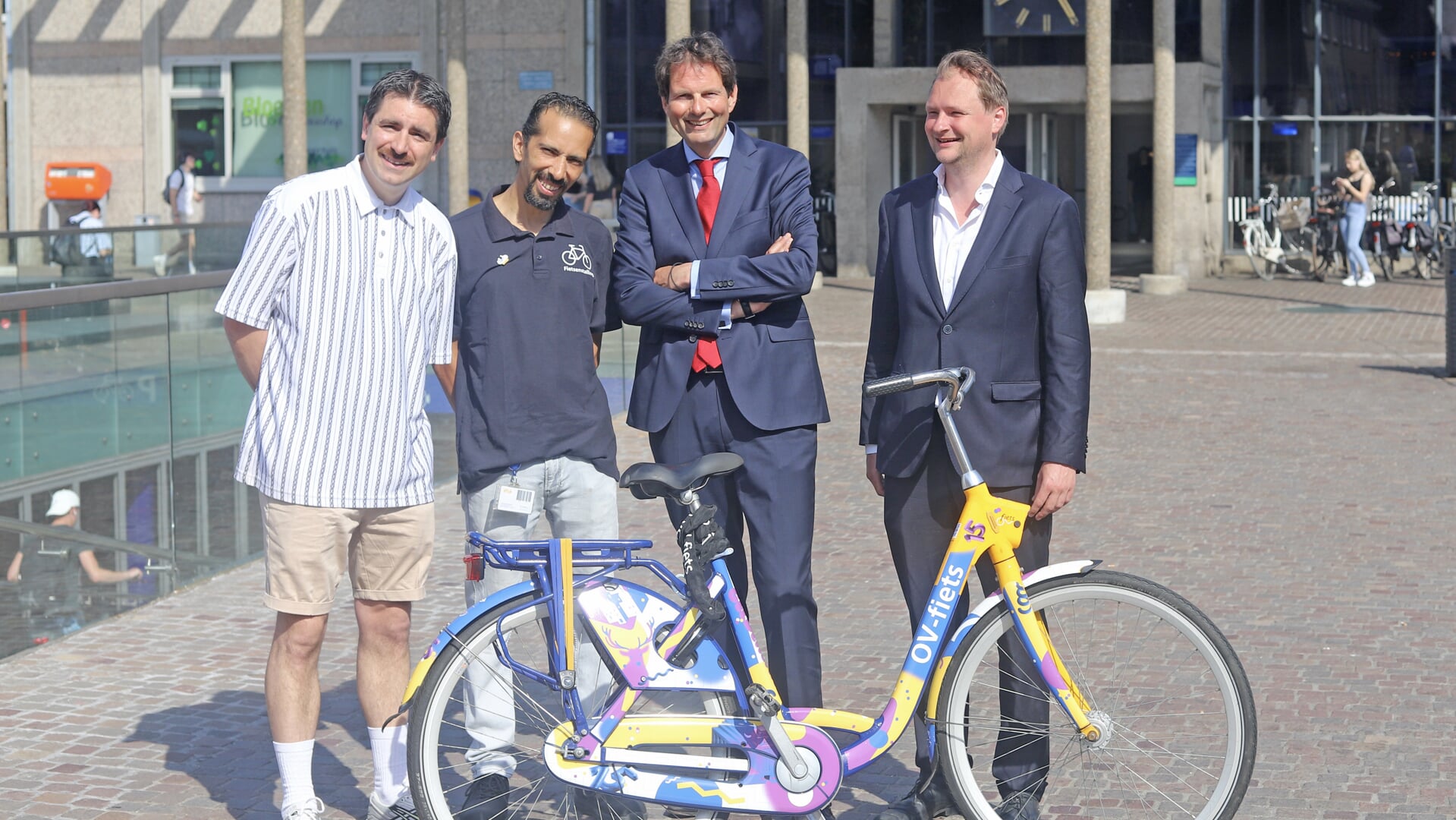 Daniël Roozenboom (kunstenaar), Amine El Kanouni (fietsenstalling), Maarten Haverkamp (NS) en Sjoerd Wannet (wethouder) poseren vóór het station met de feestfiets. Foto: Sander Grootendorst