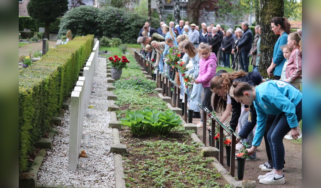 Bij de veerentwintig oorlogsgraven van de geallieerden, deden de kinderen ter nagedachtenis een bloem in de vaas. Foto: Arjen Dieperink