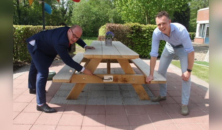 Burgemeester Joris Bengevoord (l) en Constantijn Schreiber bevestigen samen het naamplaatje van houthandel Nijweide op de picknicktafel. Foto: Lineke Voltman