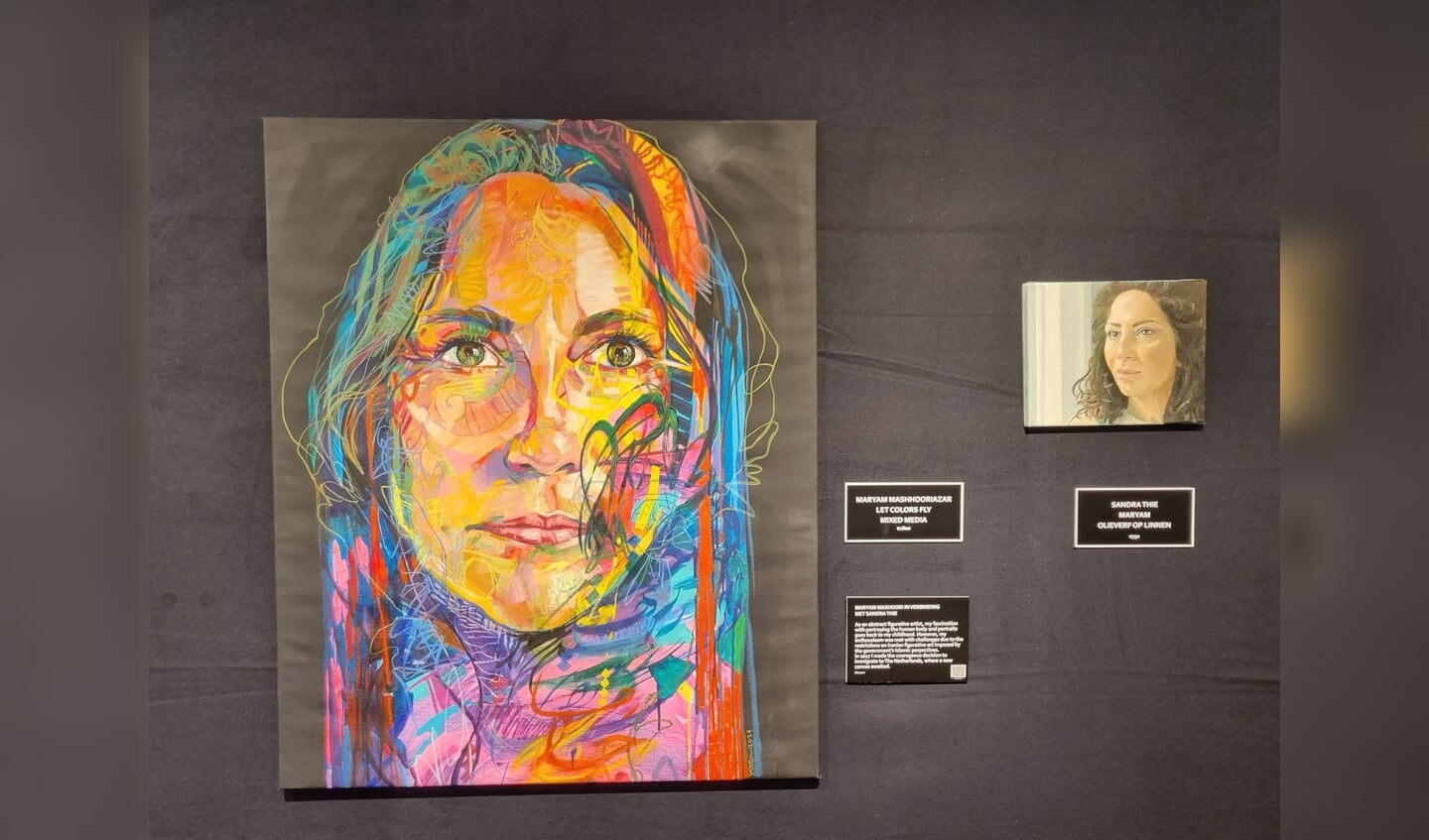 Schilderij op de expositie van de van oorsprong Iraanse Maryam Mashhoori met de titel ‘Let’ colors fly mixed Media’, met naast haar het portret van haarzelf gemaakt door Sandra Thie. Foto: Rob Weeber 