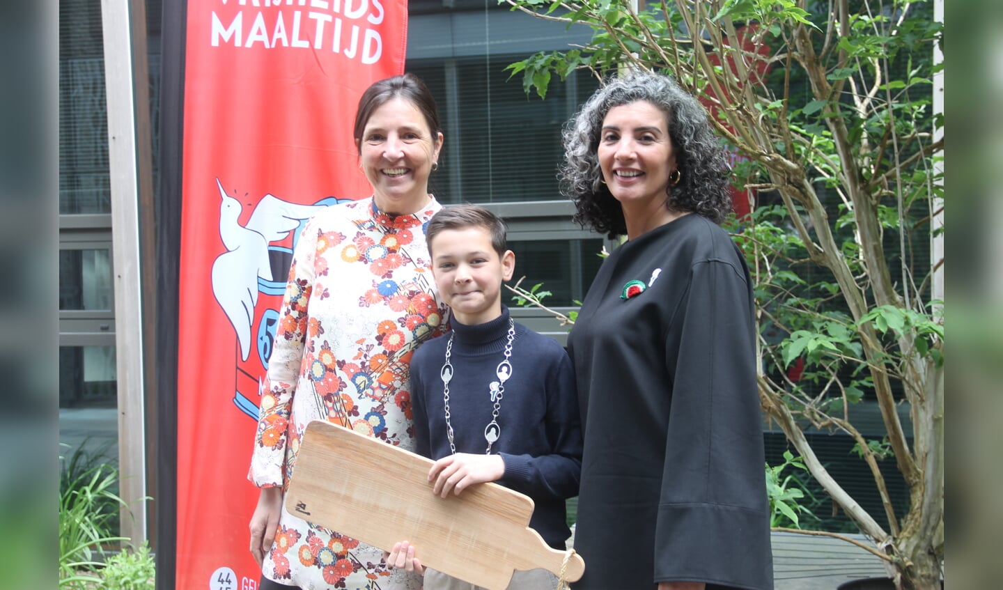 Nadia Zerouali en Frederieke Jeletich ontvangen van kinderburgemeester Josua Beijers een borrelplank. Foto Lineke Voltman