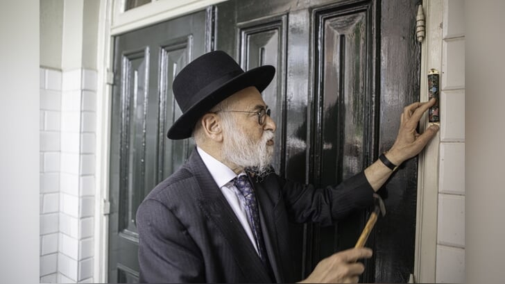 Opperrabbijn Binyomin Jacobs spijkerde zondagmiddag een mezoeza, met daarin een tekst uit de Thora, op de deurpost van de synagoge. Foto: Kitty Catharina de Fauw.