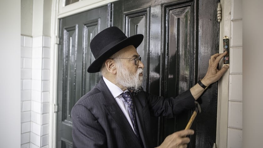 Opperrabbijn Binyomin Jacobs spijkerde zondagmiddag een mezoeza, met daarin een tekst uit de Thora, op de deurpost van de synagoge. Foto: Kitty Catharina de Fauw.