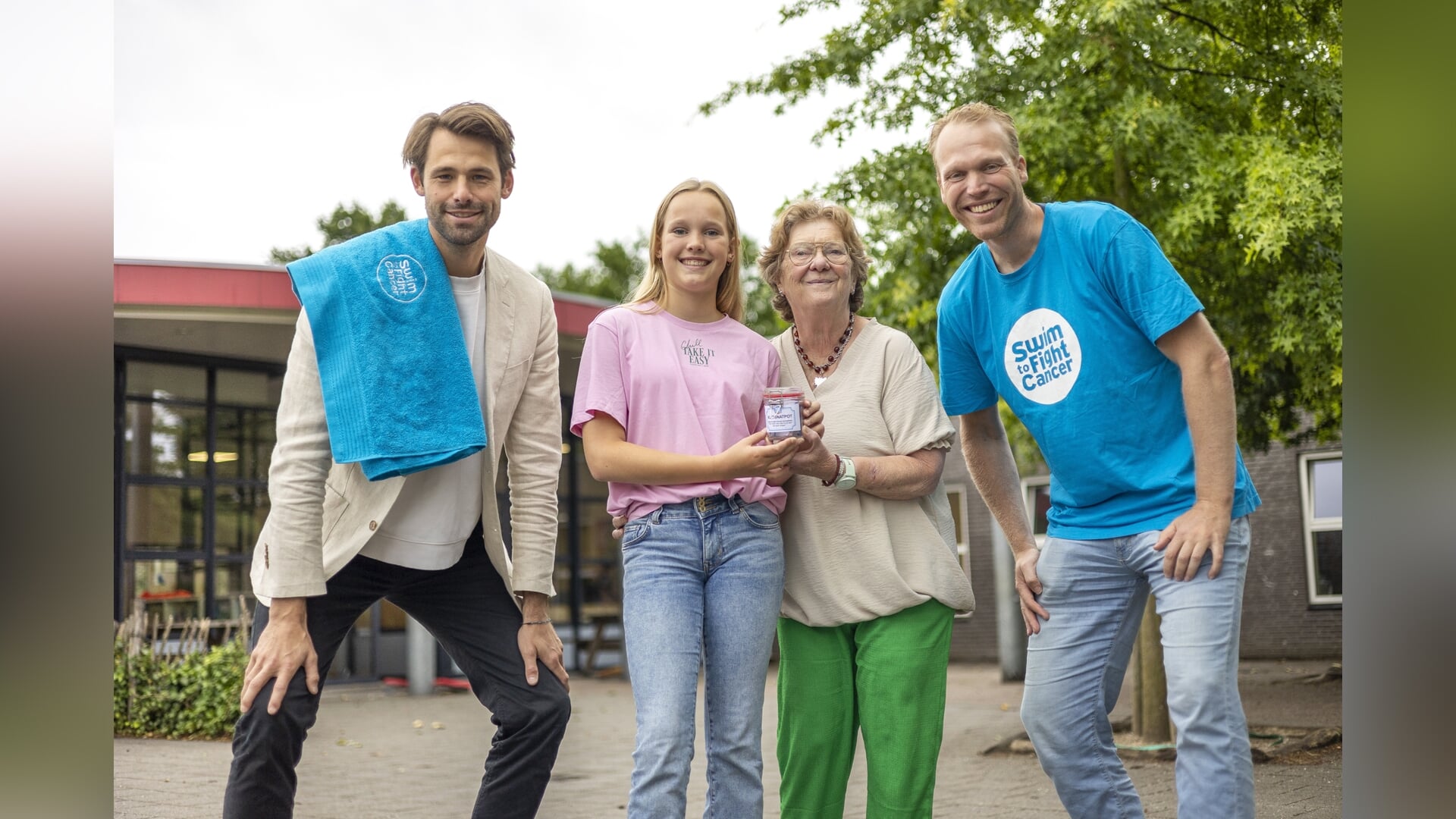 Maud Engelbarts en haar oma Ellen namen vrijdagochtend op de Roncallischool in Zeddam de allereerste Kletsnatpot in ontvangst. Naast hen Sjoerd Weikamp (rechts) van Swim to Fight Cancer Achterhoek en Joost Reijns, directeur van de landelijke organisatie. Foto: Luuk Stam 
