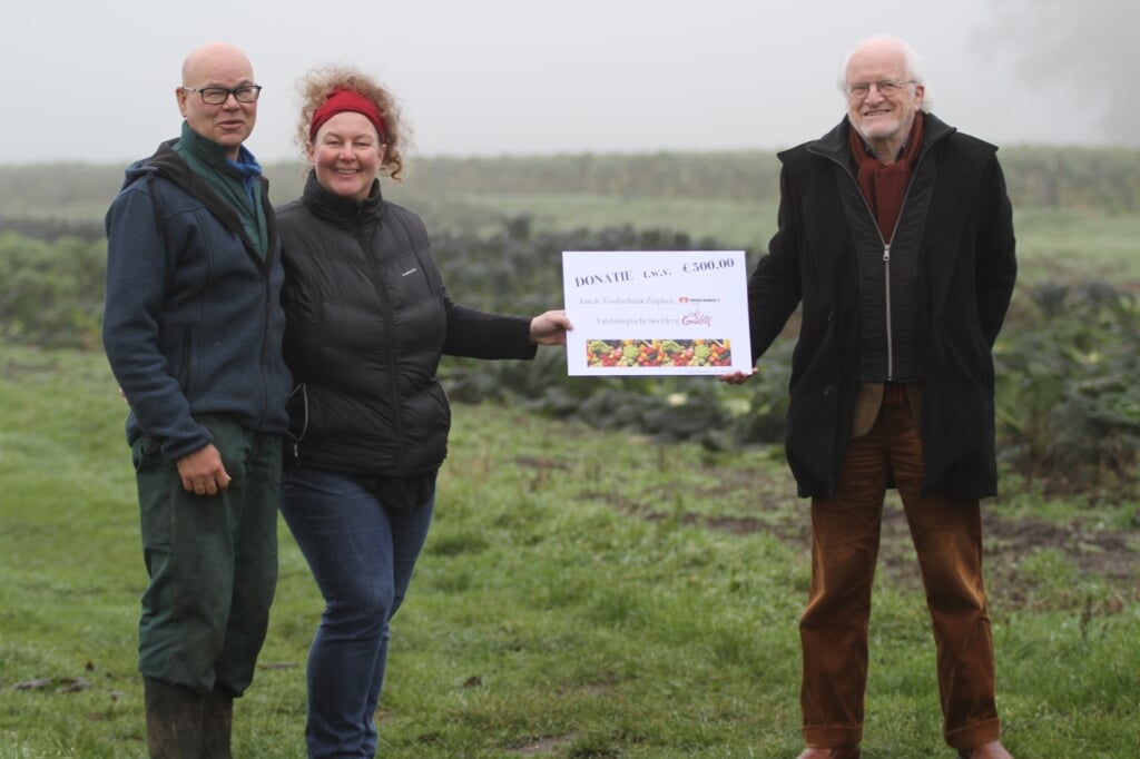 Wim Schoemaker en Rieke Griffioen overhandigen de cheque op hun boerderij aan Gert Vrieze van de Voedselbank Zutphen. Foto: Hans Dijk 
