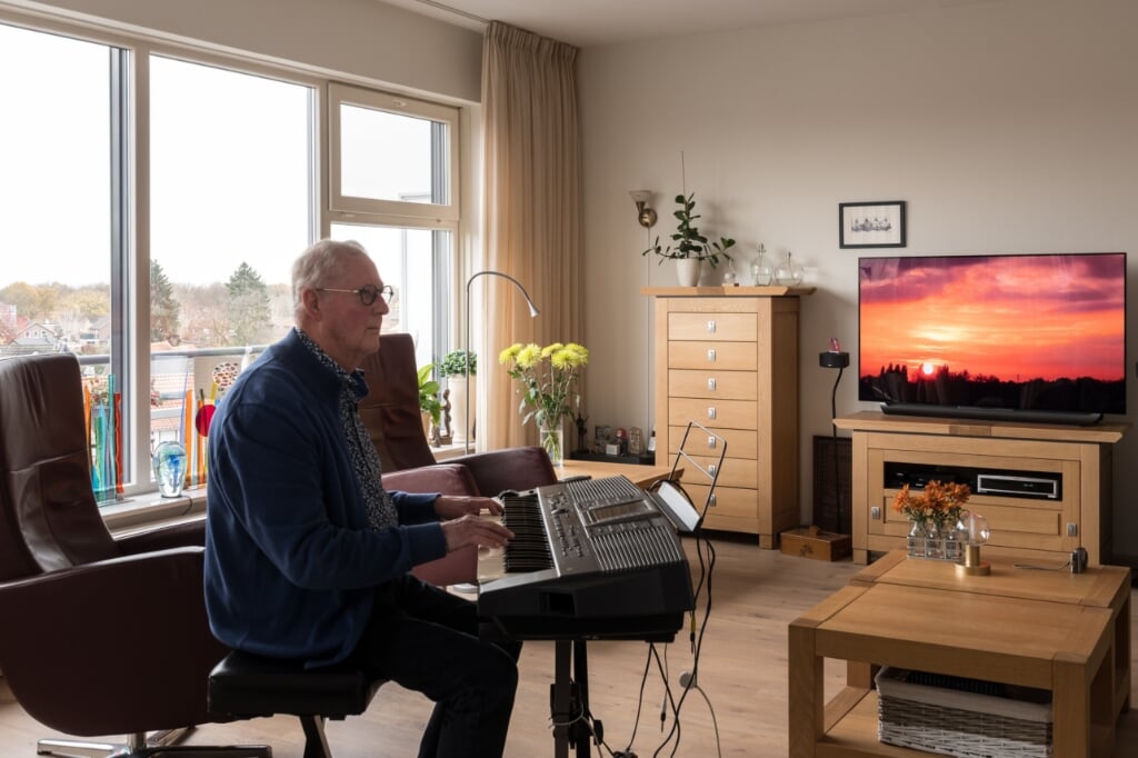 Henk Baars achter zijn keyboard met rechts op een groot scherm een video van zijn hand. Foto: Janette van Egten