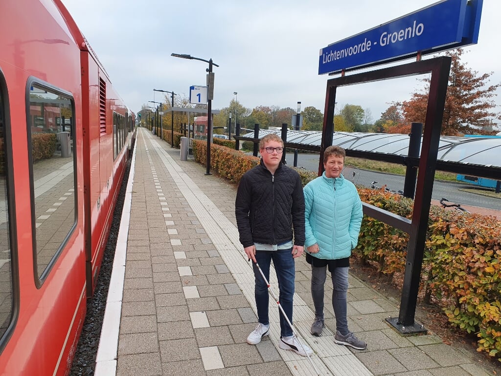 Jeffrey met moeder Francis op het perron in Lievelde, staand op de geleide lijnen waar hij van afhankelijk is met het reizen.