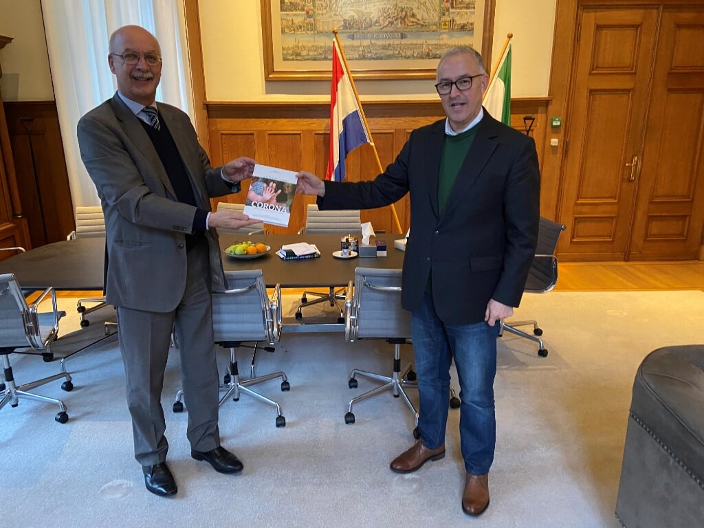 Crisisexpert Gert-Jan Ludden overhandigt het nieuwe boek 'Leren van corona - inspirerende inzichten vanuit de praktijk' aan de Rotterdamse burgemeester Ahmed Aboutaleb. Foto: Bas Eenhoorn