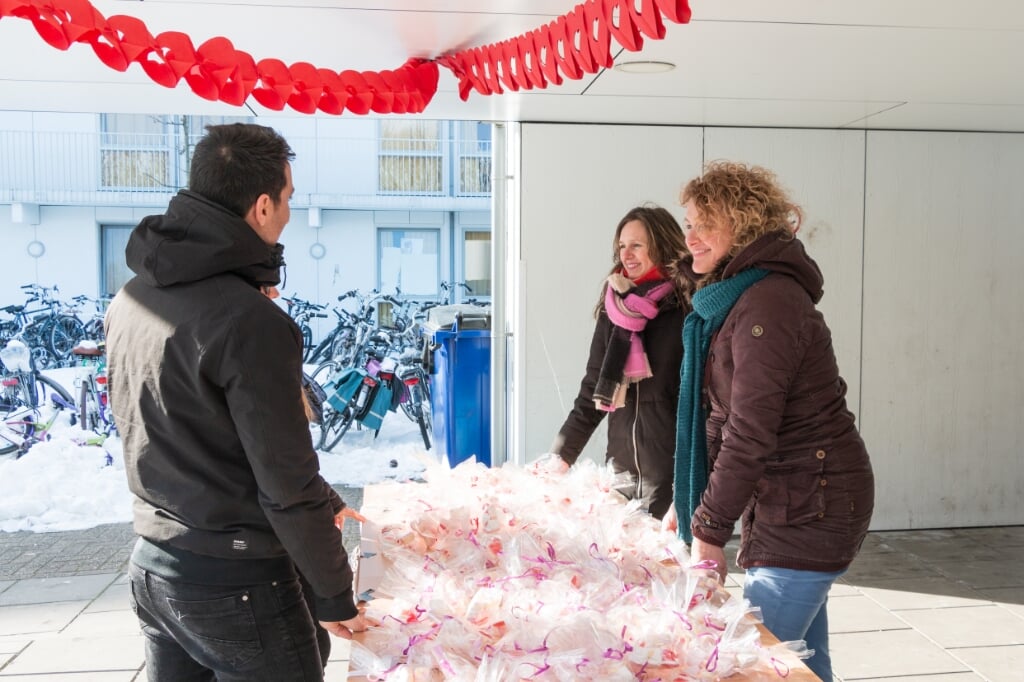 Andrea (midden) en Annelies van Koffiehuis Sparkle delen zakjes hartensnoepjes uit aan bewoners AZC. Foto: Henk Derksen