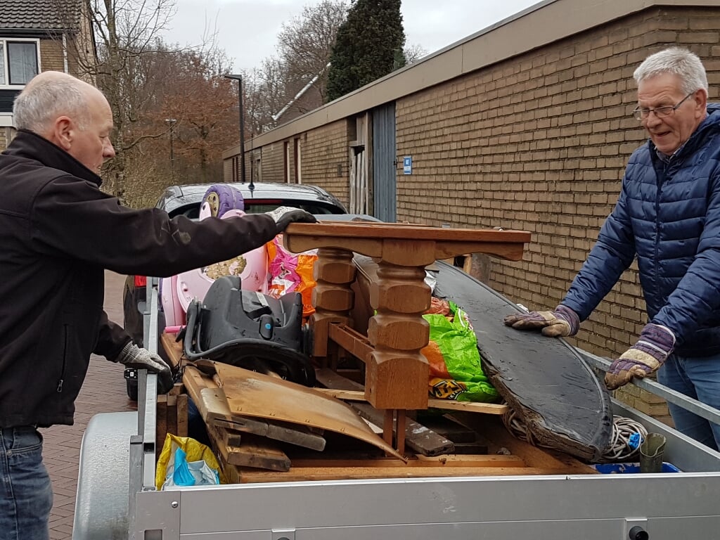 Twee vrijwilligers laden een aanhangwagen vol met grof vuil. Foto: Present Winterswijk