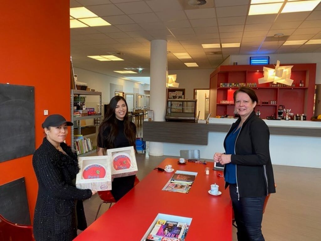 PvdA-Raadslid Marjolijn Moester reikt twee rode taarten uit aan huiswerkbegeleiders Andrea Vetkamp (links) en Melatie van Beem (midden). Foto: PR
