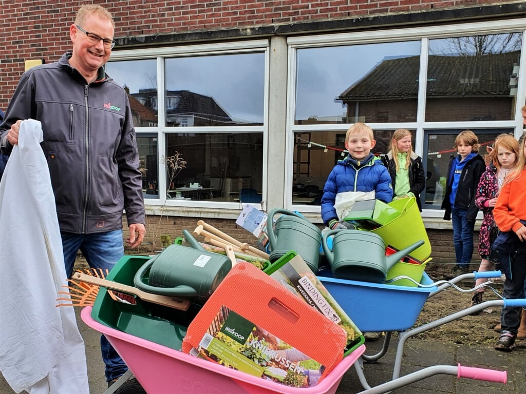 Paul Harmelink van Welkoop Vorden en Matthias Wibier onthulden de tjokvolle kruiwagens met zaden en gereedschap voor de schoolmoestuin. Foto: Alice Rouwhorst